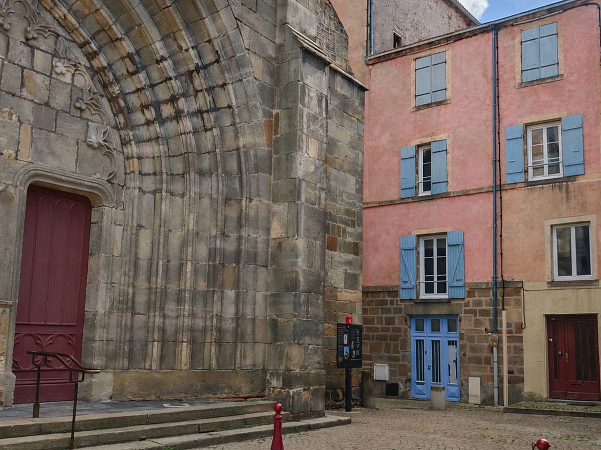 La place de l'église de Vic-le-Comte et la façade rose de l'immeuble